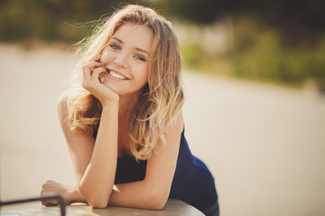 Fototapeta premium Portrait of a young beautiful smiling blonde woman outdoors