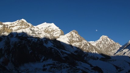 Rising moon over snow capped mountains