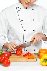 Beautiful young woman cook cutting fresh tomatoes