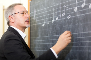 Music teacher writing notes on a blackboard