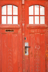 Closed old red door with blanched paint