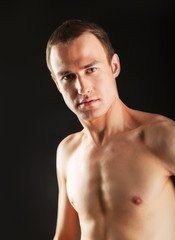 Naklejka premium Portrait of a naked muscular man, isolated on black background.