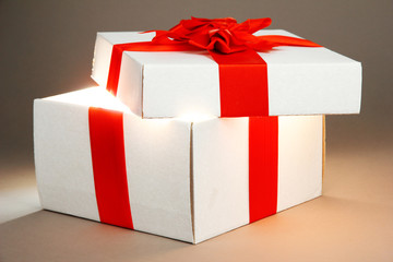 Gift box with bright light on it on grey background