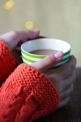Hands holding mug of hot drink, close-up, on bright background