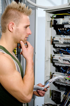 Confused male electrician in front of power panel