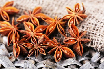 Star anise on wicker mat, on wooden background