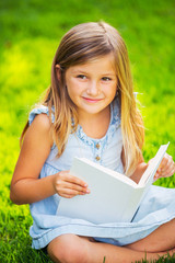 Little girl reading book outside