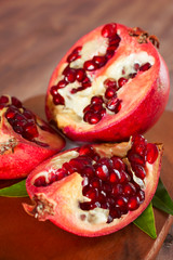 Ripe pomegranate with leaves on a wooden board.