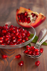 Fresh ripe pomegranate seeds on a glass plate. Wooden background