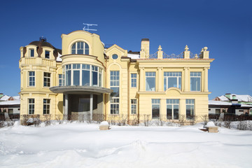 Obraz premium Beautiful two-storey yellow house and bushes on sunny frosty