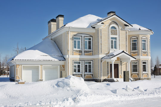 Two-storey light cottage with garage at frosty and sunny winter