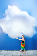 Little smiling girl holds large painted at blue wall cloud