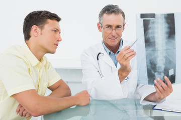 Doctor explaining spine x-ray to patient in office