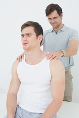 Male physiotherapist massaging a young mans shoulder