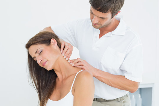 Male chiropractor massaging a young woman's neck