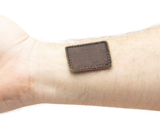 Blank leather label sewed on a hand isolated over white