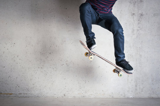 Skateboarder doing a skateboard trick - ollie - against concrete
