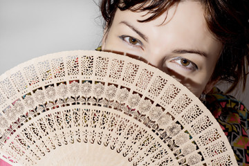Beautiful woman partly hidden behind a fan