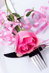 romantisch gedeckter tisch mit silberbesteck und einer rose