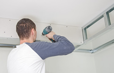 Builder mounting gypsum plasterboard frame on the wall