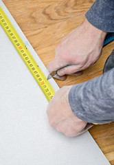 Male hands measuring and cutting gypsum plasterboard