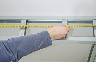Male hands measuring gypsum plasterboard frame