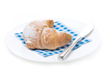 fresh croissant and a knife on a white plate, isolated