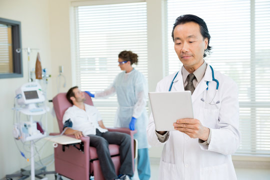 Doctor Using Digital Tablet In Chemo Room