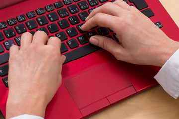 Frau arbeitet an einem roten Laptop