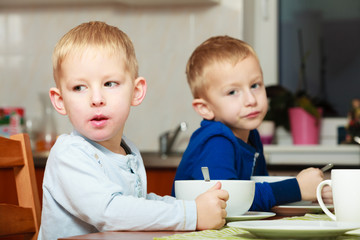 Boys kids children eating corn flakes breakfast at the table