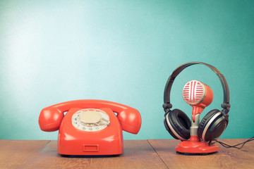Retro red microphone, headphones and telephone on table