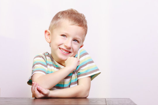 Portrait of happy laughing blond boy child kid at the table