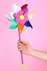 Colored pinwheel in hand on pink background