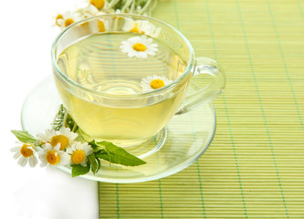 Cup of herbal tea with wild camomiles and mint, isolated
