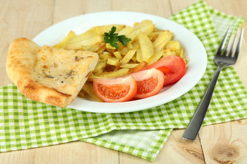 Fried potatoes on plate on wooden table close-up