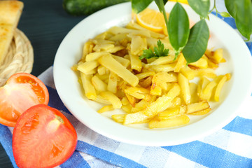 Ruddy fried potatoes on plate on tablecloth close-up