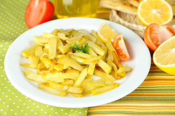 Ruddy fried potatoes on plate on tablecloth close-up
