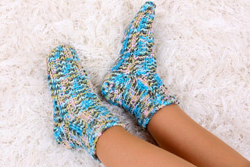 Female legs in colorful socks on white carpet background