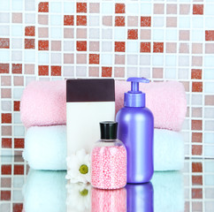 Cosmetics and bath accessories on mosaic tiles background