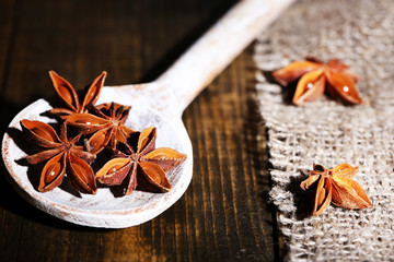 Star anise in wooden spoon, on wooden background