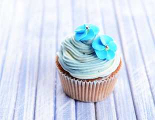 Tasty cupcake with butter cream, on color wooden background