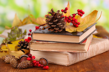 Books and autumn leaves on wooden table on natural background