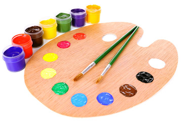 Wooden art palette with paint and brushes isolated on white