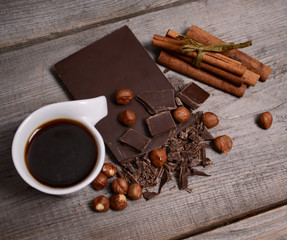 Pieces of dark chocolate and black coffee on a wooden background