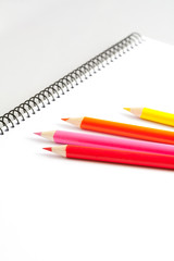 Open sketchbook with clear page with colored pencils on gray background.