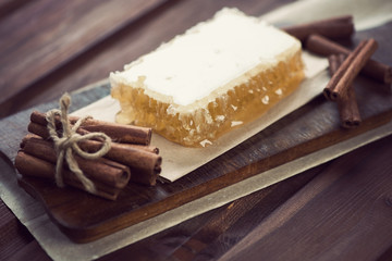 Cinnamon sticks and a honeycomb on a vintage cutting board