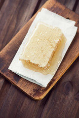 Above view of a honeycomb on a rustic wooden cutting board