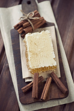 Cutting board with a honeycomb and cinnamon sticks, above view