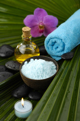 Fototapeta na wymiar candle, oil ,salt in bowl ,candle ,towel on palm leaf texture
