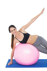 Fototapeta na wymiar Portrait of a fit woman stretching on fitness ball